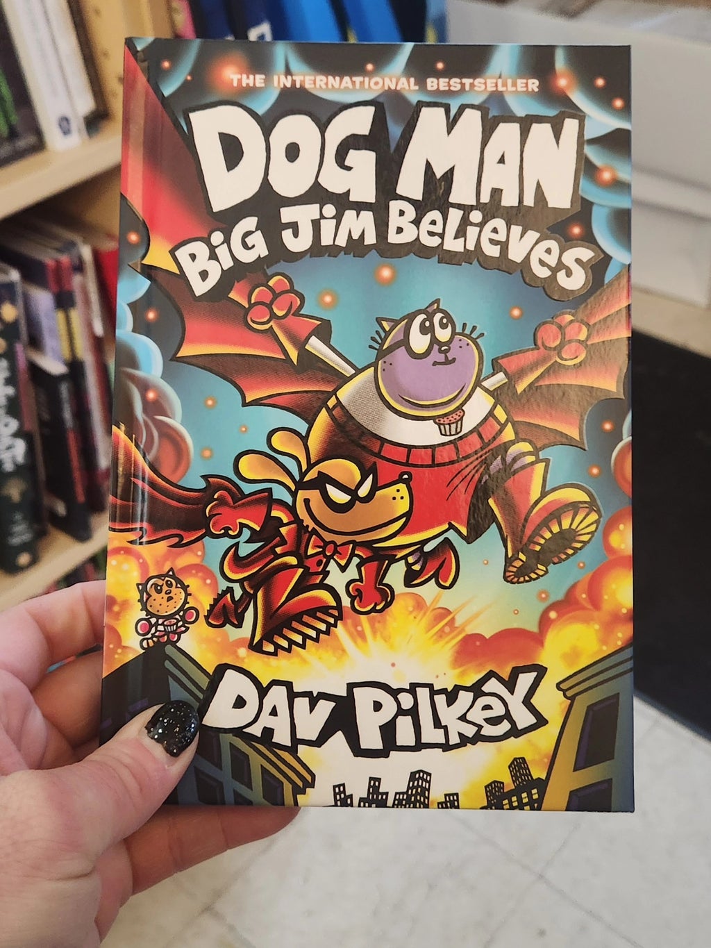  im holding a copy of the new dog man book by dav pilkey.